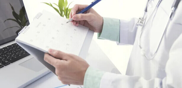 An anesthesiologist marking a date on a calendar, planning medical appointments